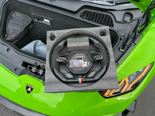 Carbon fiber steering wheel displayed on engine bay of green sports car