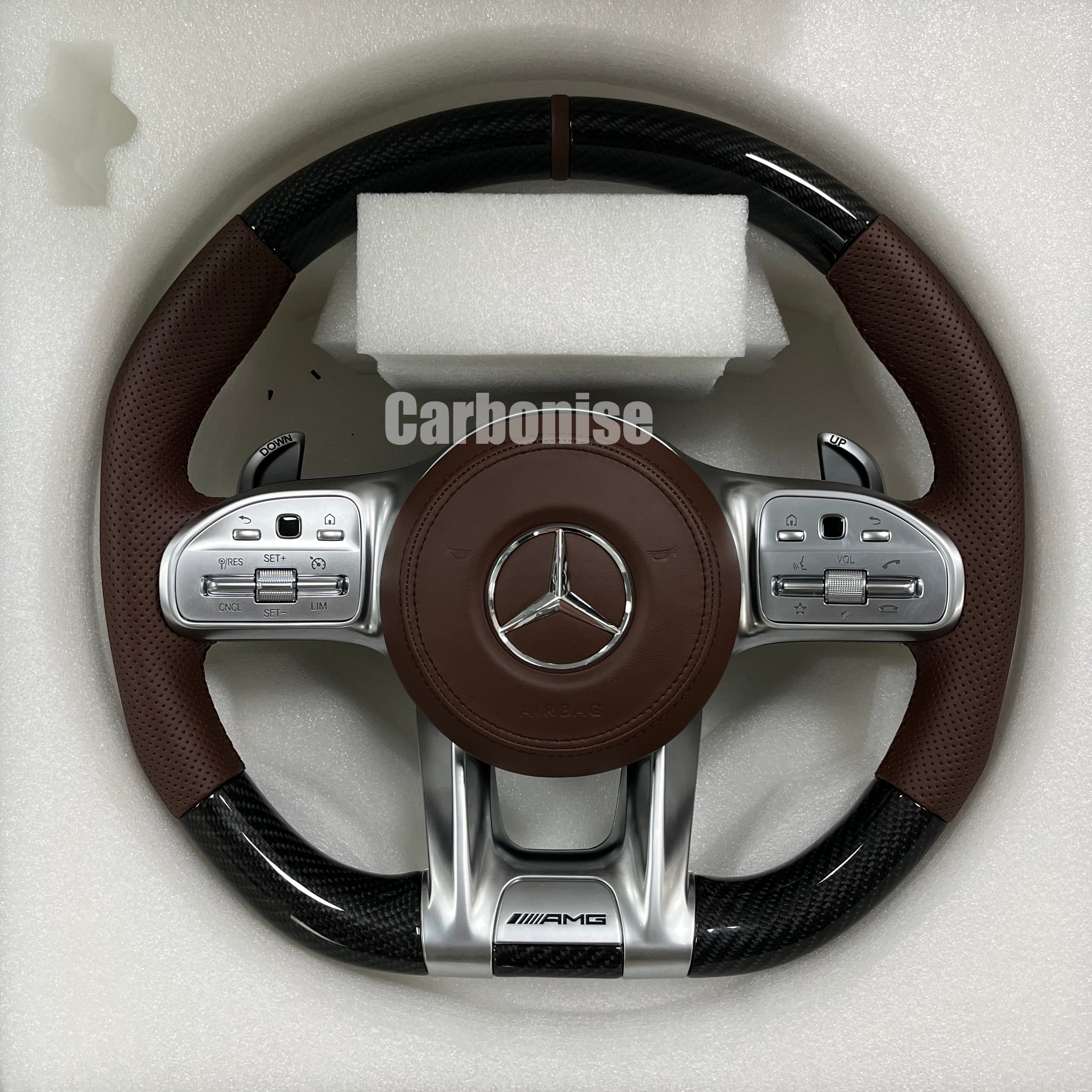 Custom Mercedes-Benz AMG steering wheel featuring gloss carbon fiber, premium brown perforated leather side grips, and integrated silver roller controls.