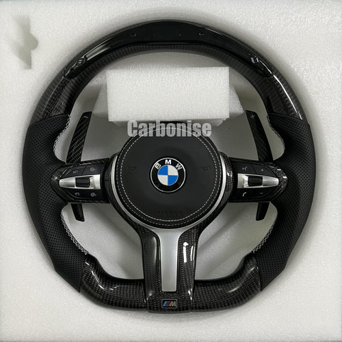 Custom BMW M Performance steering wheel featuring a gloss carbon fiber top and bottom, black perforated leather side grips with white contrast stitching, and matching carbon fiber paddle shifters.