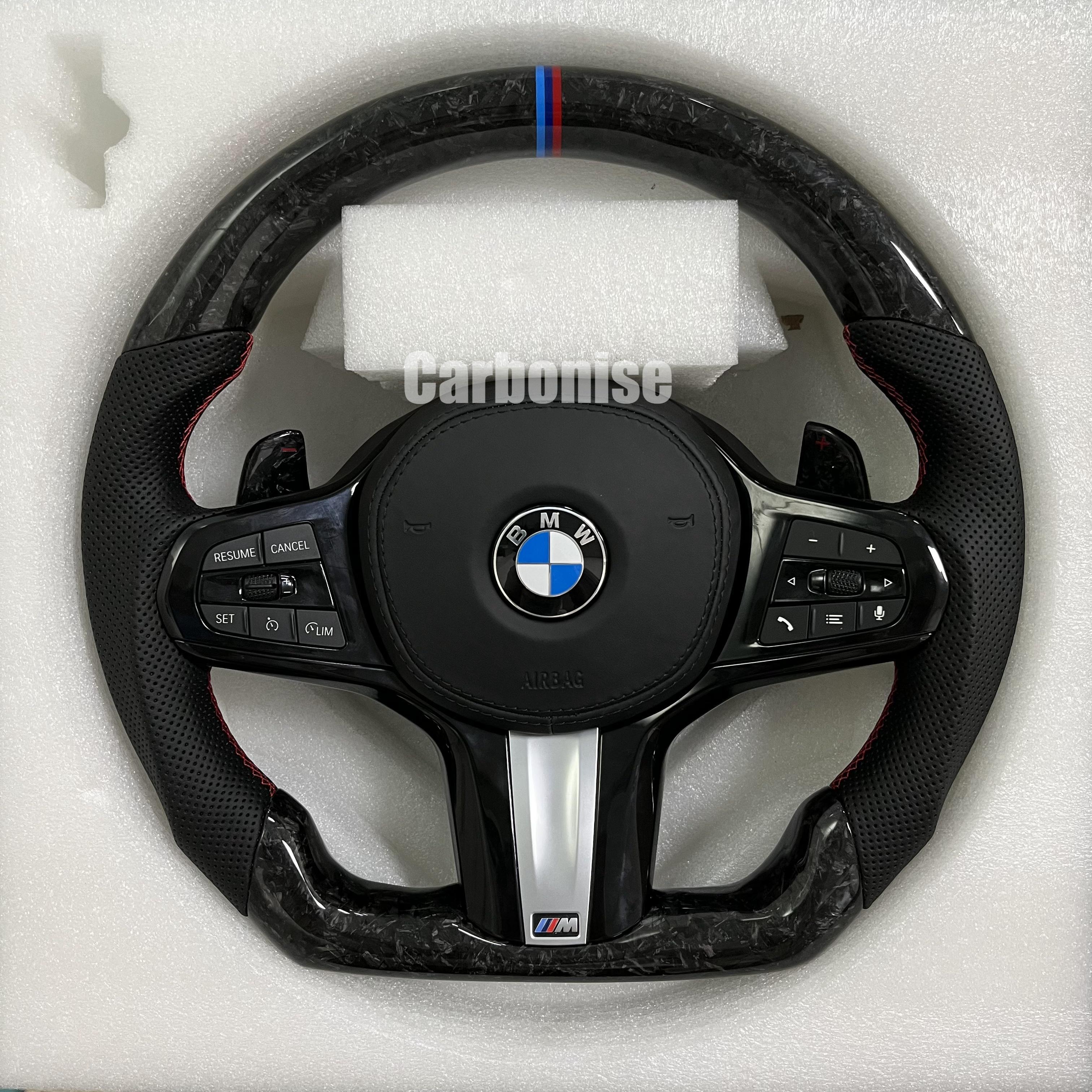 Custom BMW M performance steering wheel featuring a forged carbon fiber finish, black perforated leather side grips, and a signature M-tri color top racing stripe.