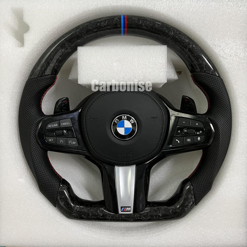 Custom BMW M performance steering wheel featuring a forged carbon fiber finish, black perforated leather side grips, and a signature M-tri color top racing stripe.