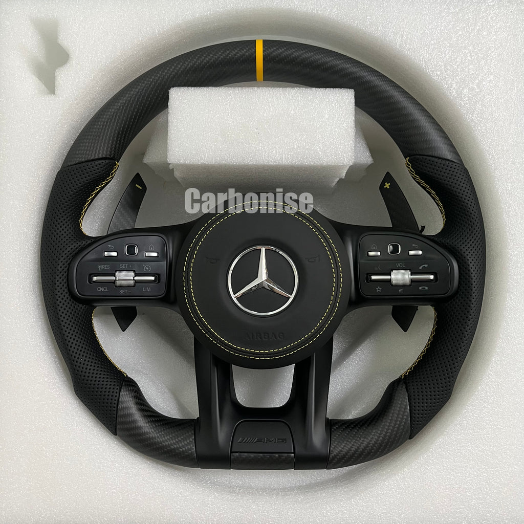 Custom Mercedes-Benz AMG steering wheel featuring a matte carbon fiber finish, black perforated leather side grips with yellow stitching, and a yellow top racing stripe.