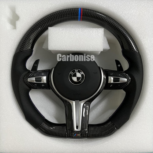 Custom BMW M Performance steering wheel featuring gloss carbon fiber, a signature blue, light blue, and red M-tri color top racing stripe, and black perforated leather side grips with blue contrast stitching.