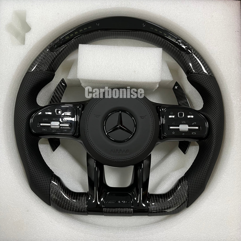 Custom Mercedes-Benz AMG performance steering wheel featuring gloss carbon fiber, a digital LED display, and black perforated leather side grips.
