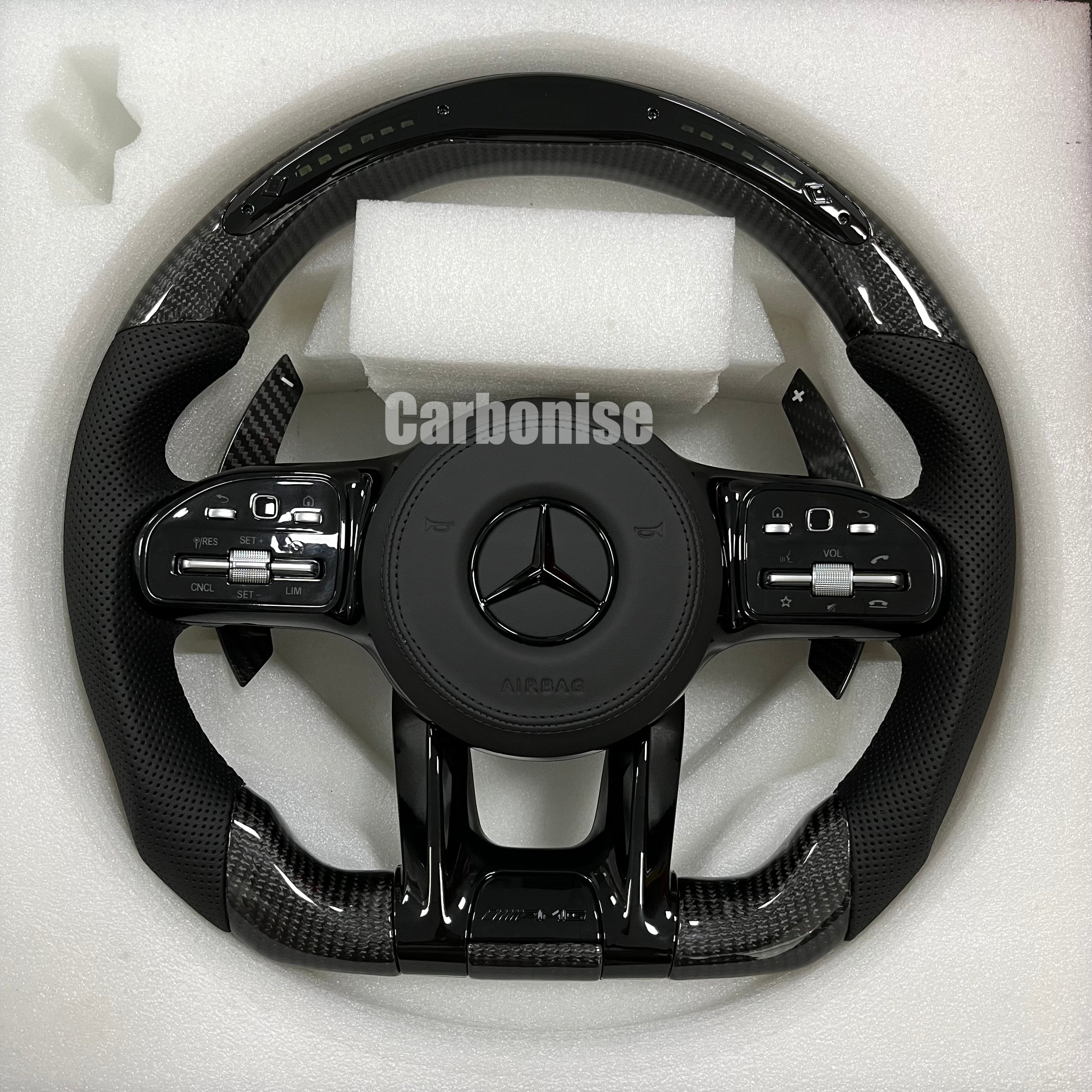 Custom Mercedes-Benz AMG performance steering wheel featuring gloss carbon fiber, a digital LED display, and black perforated leather side grips.