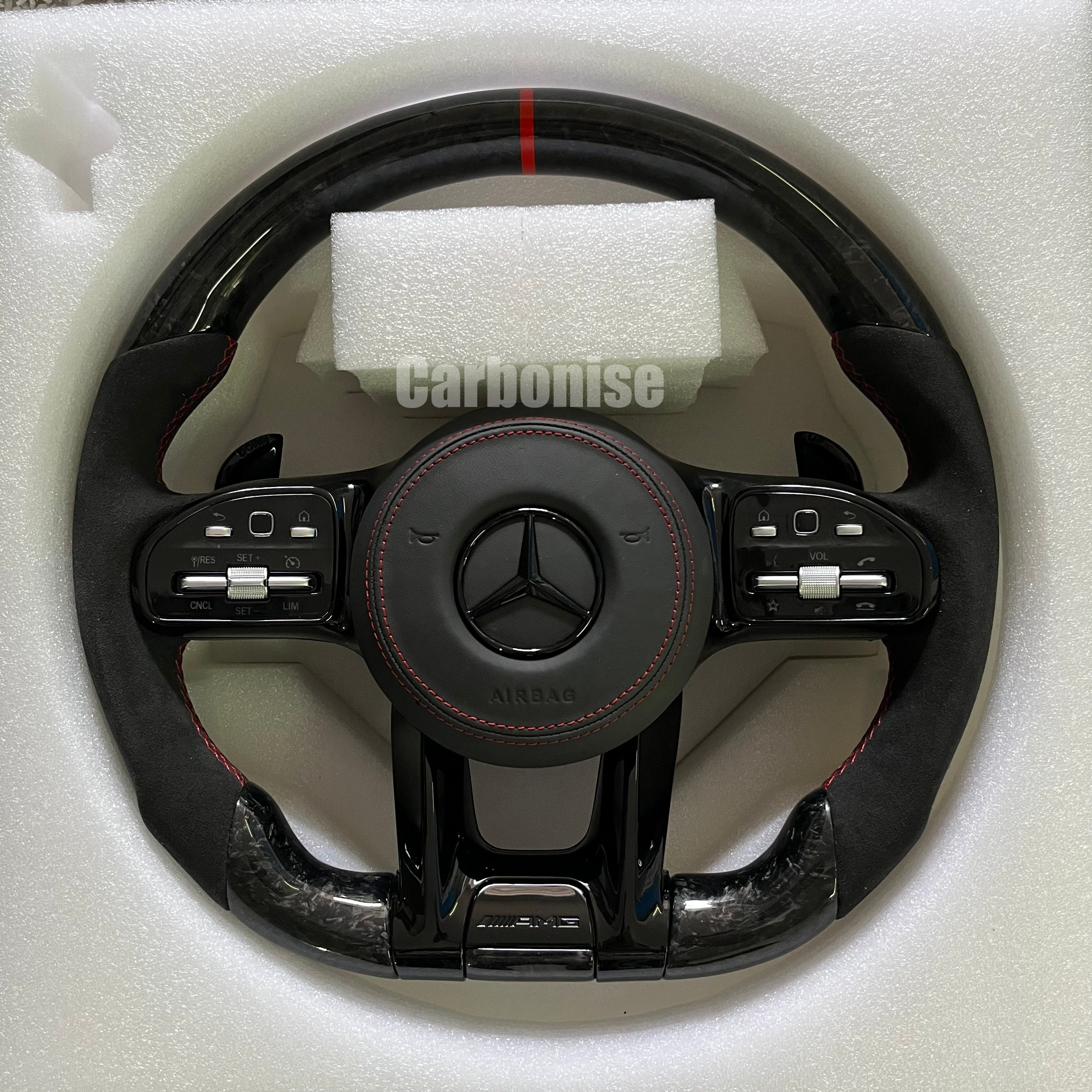 Custom Mercedes-Benz AMG steering wheel featuring high-gloss carbon fiber, a red top racing stripe, and black Alcantara side grips with red stitching.