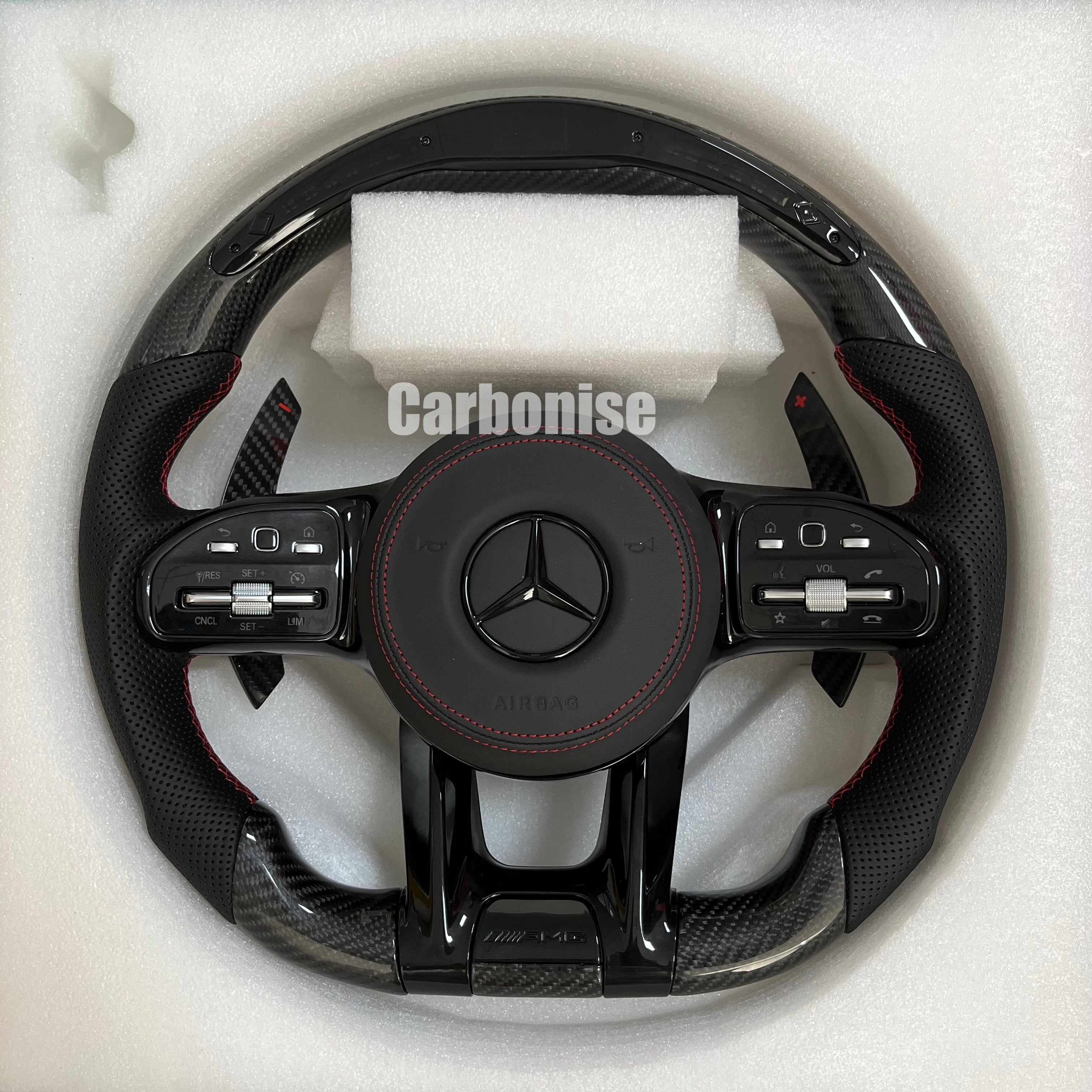 Custom Mercedes-Benz AMG steering wheel featuring gloss carbon fiber, black perforated leather side grips with red stitching, and integrated silver controls.