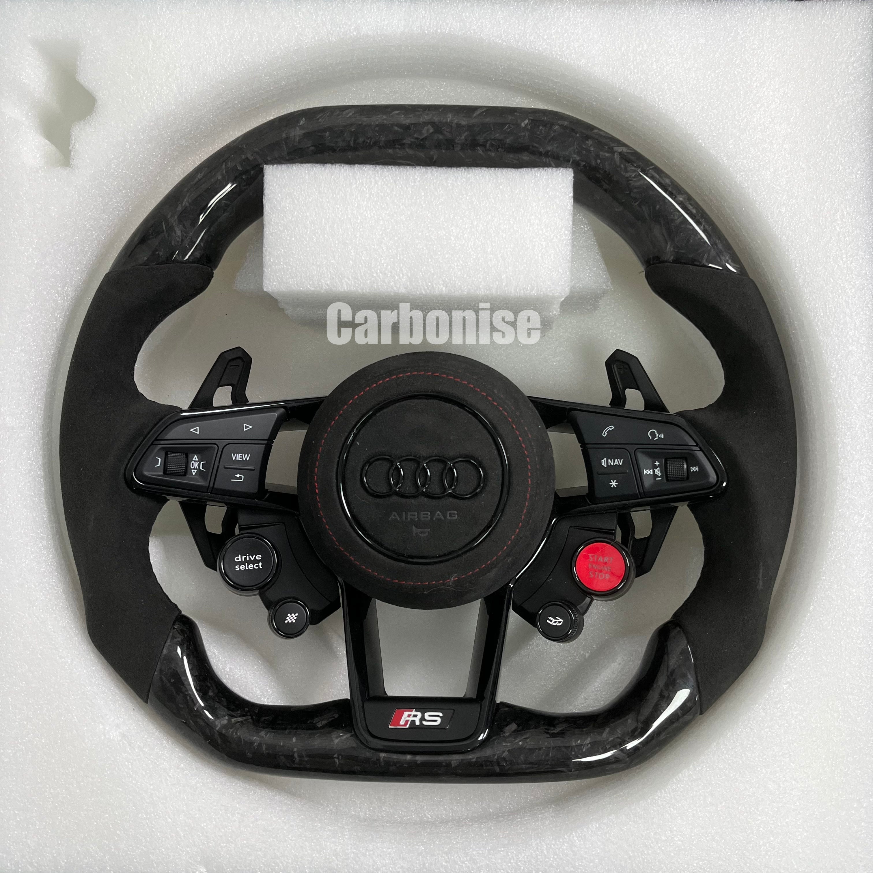 Custom Audi RS steering wheel in forged carbon fiber featuring integrated red Start/Stop and black Drive Select buttons, black Alcantara side grips with red stitching, and a blacked-out center emblem.