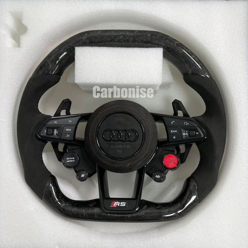 Custom Audi RS steering wheel in forged carbon fiber featuring integrated red Start/Stop and black Drive Select buttons, black Alcantara side grips with red stitching, and a blacked-out center emblem.