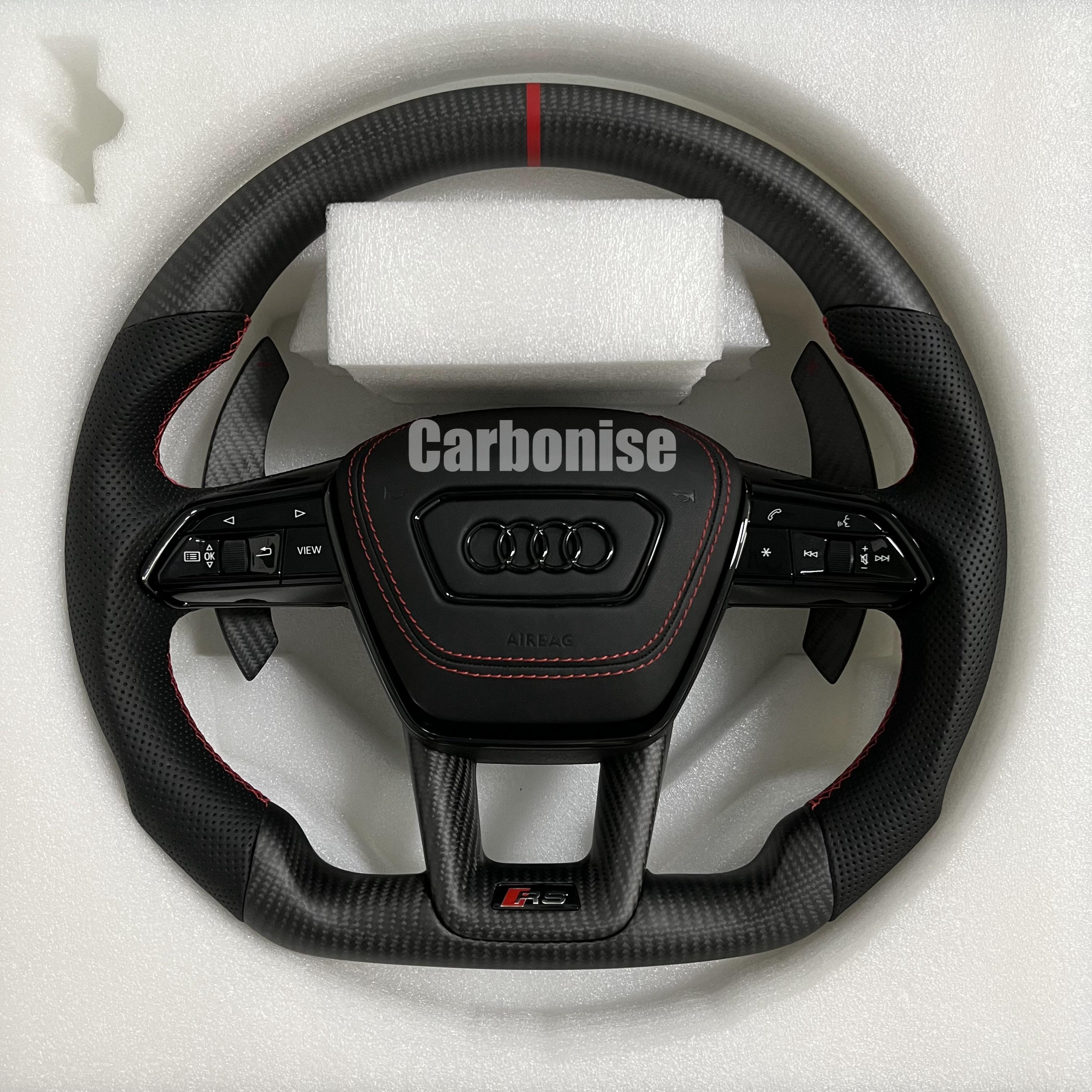 Custom Audi RS steering wheel with a matte carbon fiber finish, a red top racing stripe, and black perforated leather side grips with red contrast stitching.