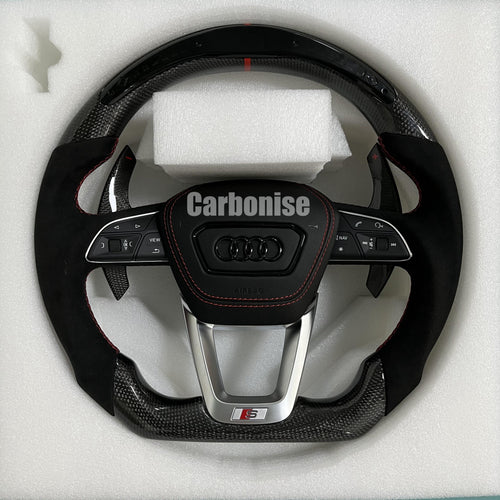 Custom Audi S performance steering wheel with gloss carbon fiber, a red top racing stripe, and black Alcantara side grips with red contrast stitching.