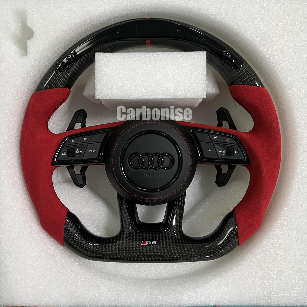 Custom Audi RS steering wheel with high-gloss carbon fiber, bright red Alcantara side grips, a red top racing stripe, and blacked-out Audi rings.