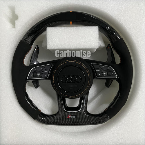 Custom Audi RS steering wheel with high-gloss carbon fiber, an orange top racing stripe, and black Alcantara side grips with orange stitching.