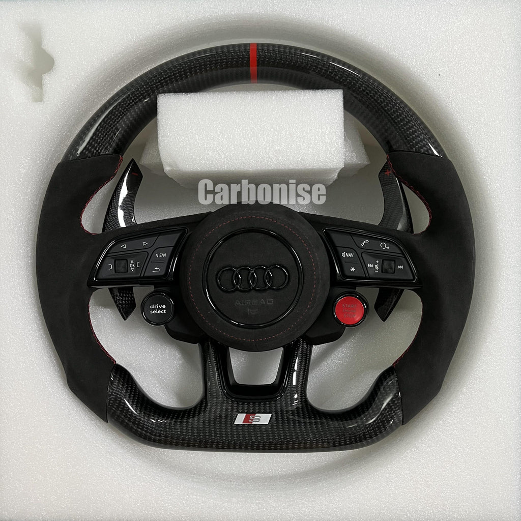 Custom Audi S performance steering wheel featuring high-gloss carbon fiber, a red top racing stripe, black Alcantara side grips with red stitching, and integrated red Start/Stop and black Drive Select buttons.