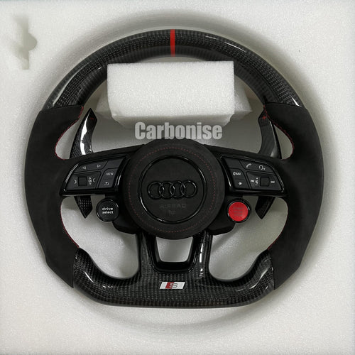 Custom Audi S performance steering wheel featuring high-gloss carbon fiber, a red top racing stripe, black Alcantara side grips with red stitching, and integrated red Start/Stop and black Drive Select buttons.