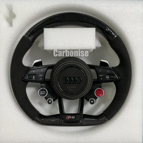Custom Audi RS carbon fiber steering wheel featuring black Alcantara side grips, gold contrast stitching, and integrated red Start/Stop and black Drive Select buttons.