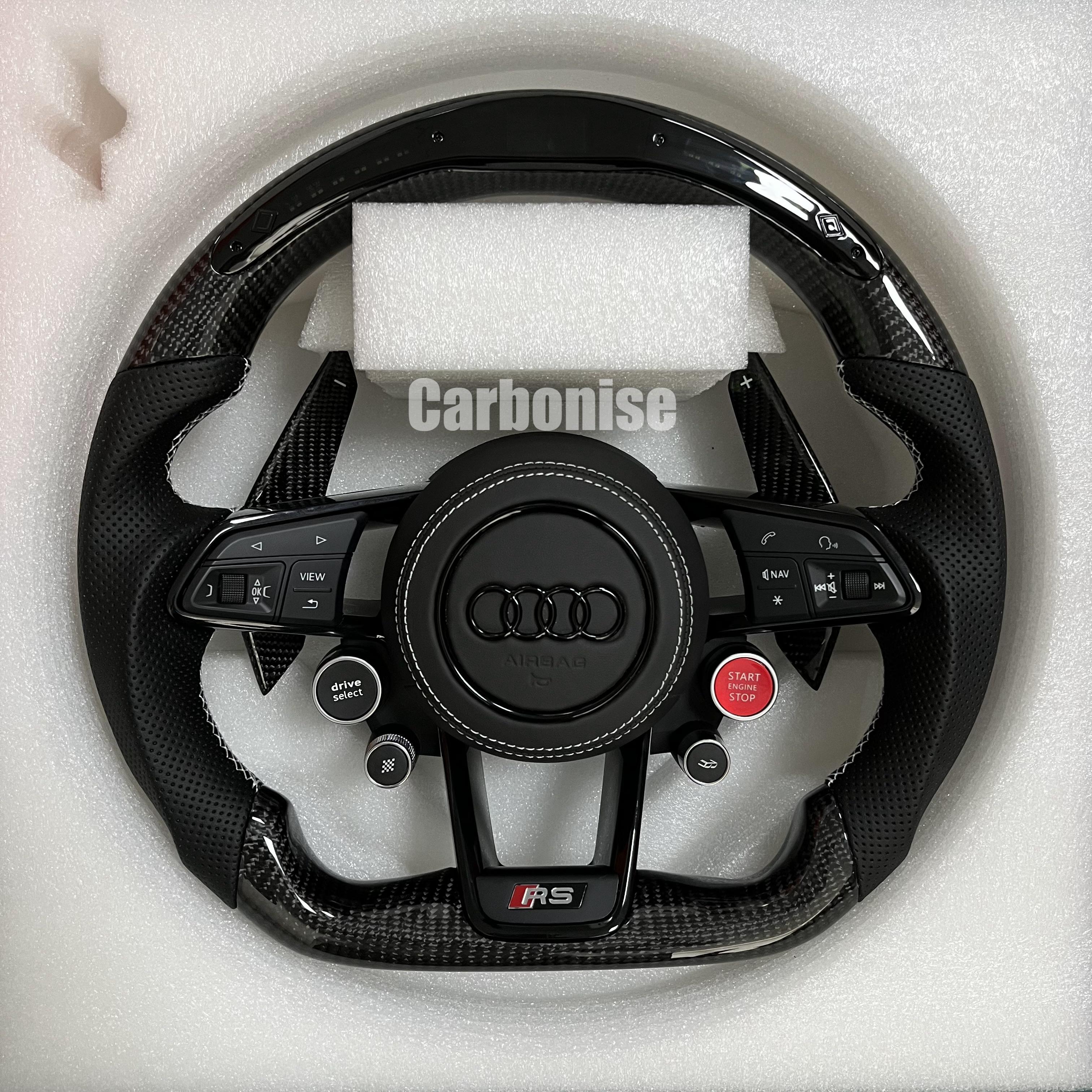 Custom Audi RS steering wheel featuring gloss carbon fiber, perforated leather grips with white stitching, integrated R8 performance buttons, and carbon fiber paddle shifters.