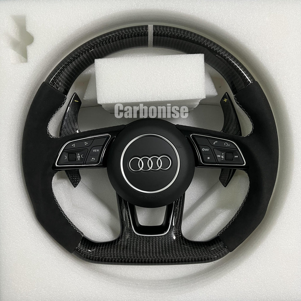 Custom Audi S-Line steering wheel featuring gloss carbon fiber, a silver top racing stripe, and black Alcantara side grips with white contrast stitching.