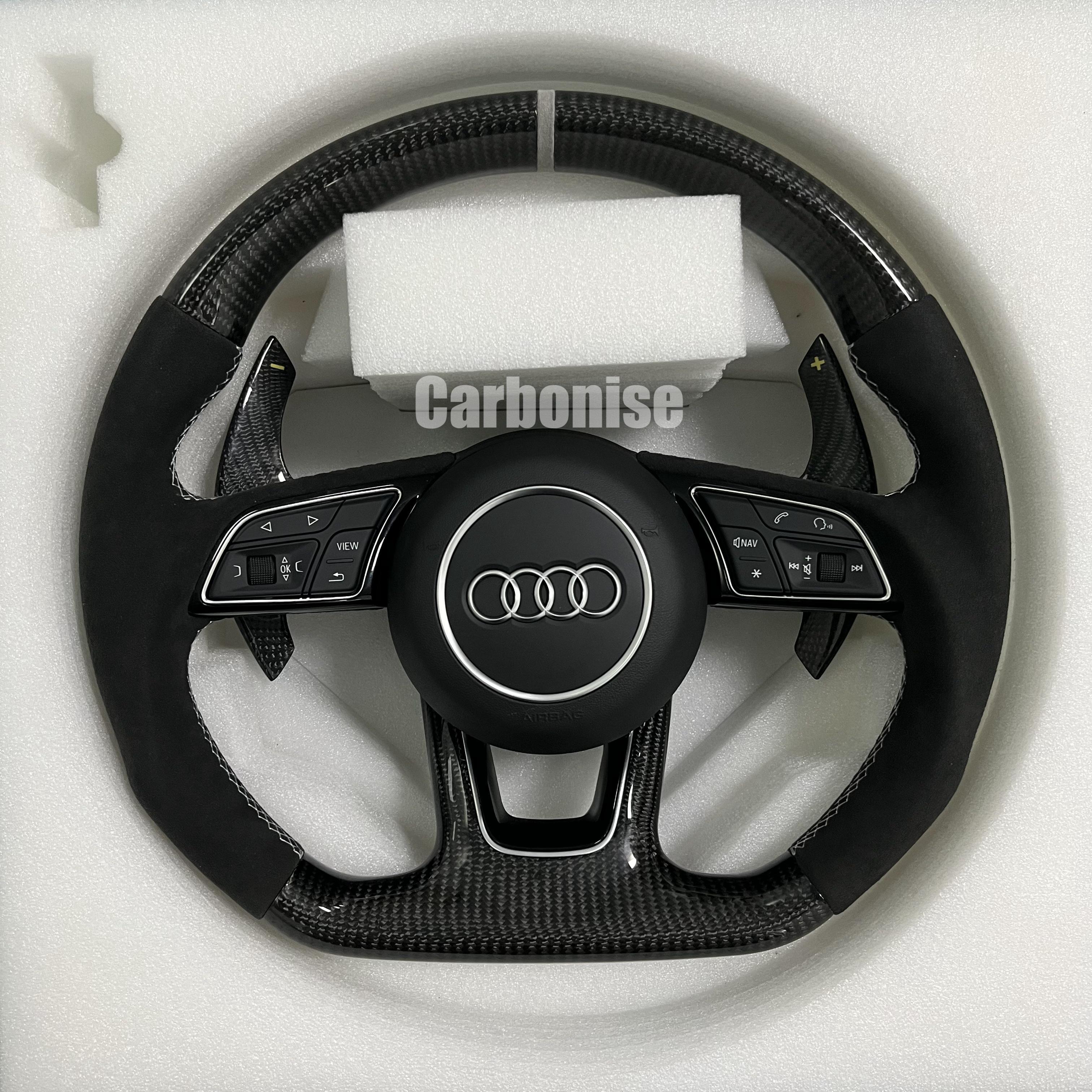 Custom Audi S-Line steering wheel featuring gloss carbon fiber, a silver top racing stripe, and black Alcantara side grips with white contrast stitching.
