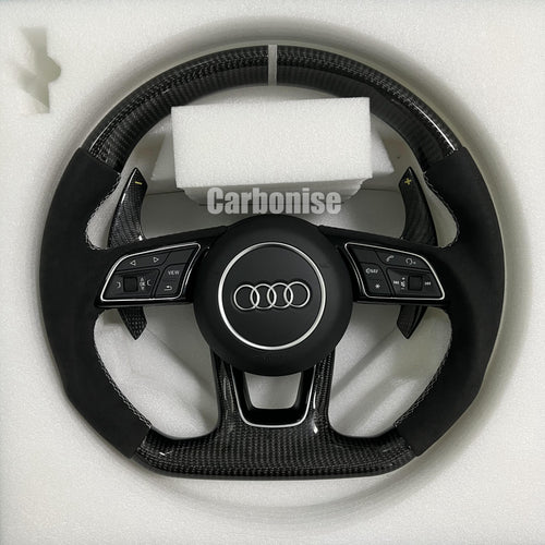 Custom Audi S-Line steering wheel featuring gloss carbon fiber, a silver top racing stripe, and black Alcantara side grips with white contrast stitching.