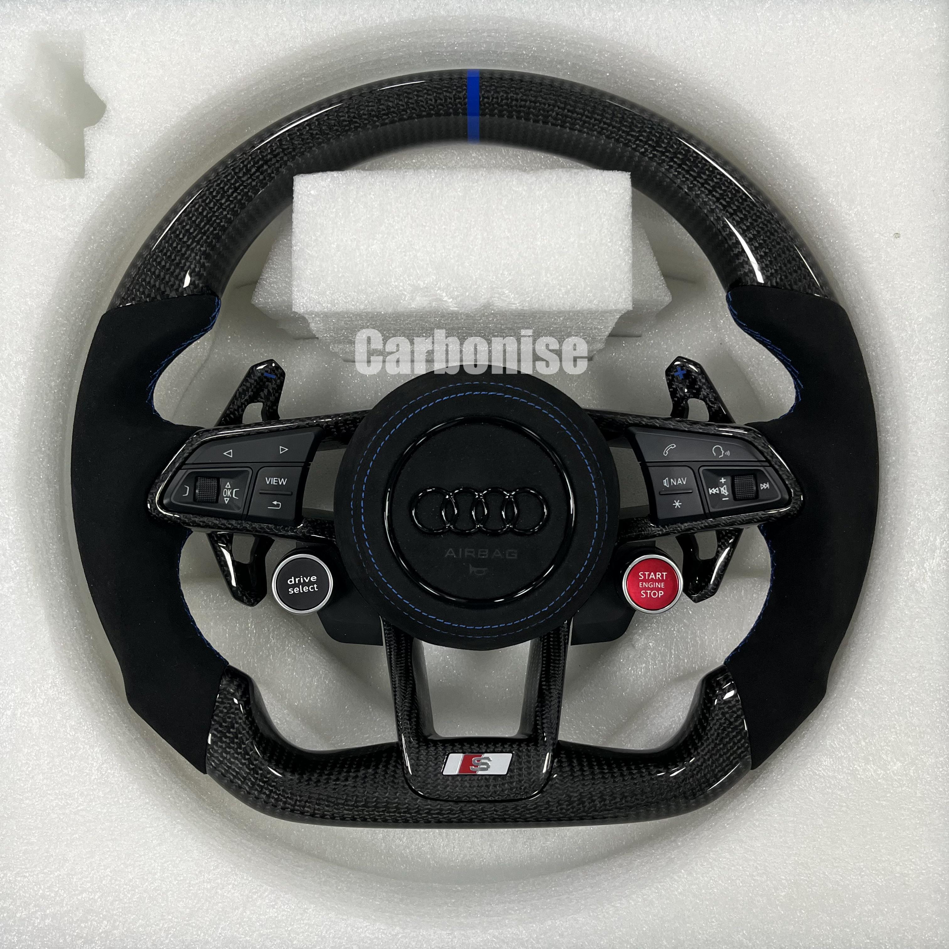 Custom Audi S performance steering wheel featuring gloss carbon fiber, a blue top racing stripe, black Alcantara side grips with blue stitching, and integrated red Start/Stop and black Drive Select buttons.