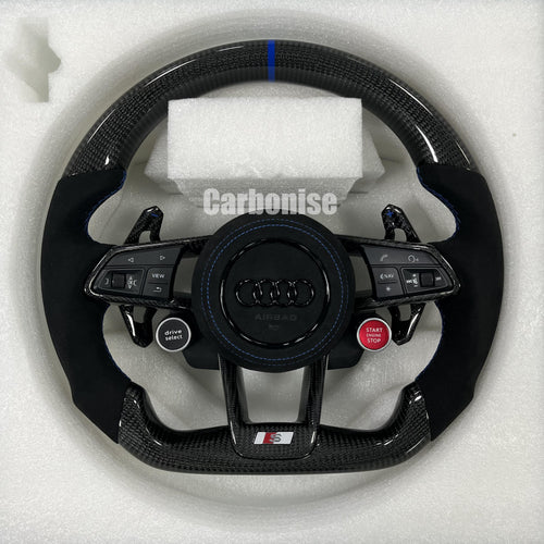 Custom Audi S performance steering wheel featuring gloss carbon fiber, a blue top racing stripe, black Alcantara side grips with blue stitching, and integrated red Start/Stop and black Drive Select buttons.