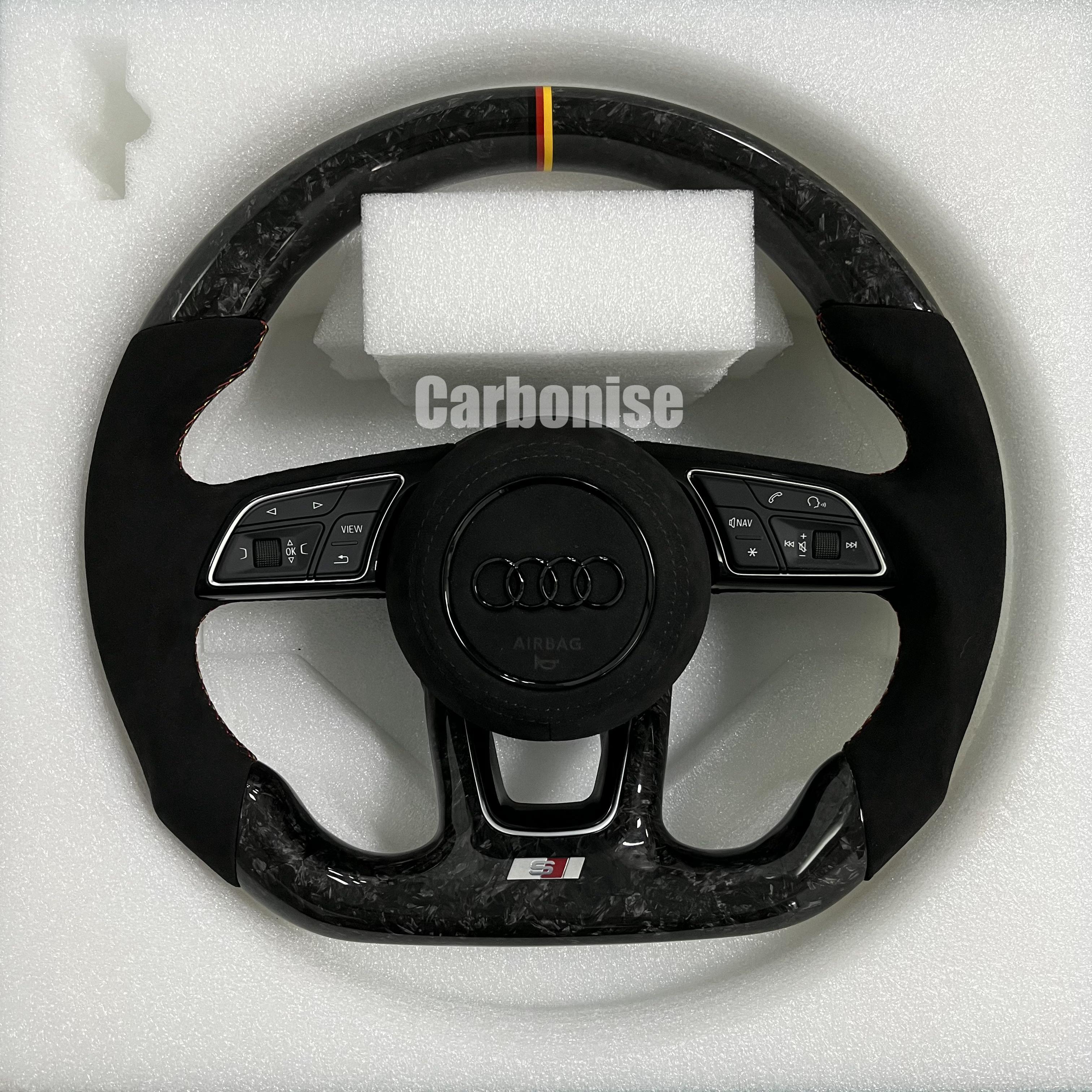 Custom Audi S steering wheel in forged carbon fiber featuring a German flag top racing stripe, black Alcantara side grips with red stitching, and blacked-out Audi rings.