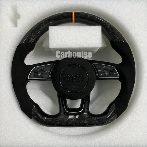 Custom Audi S steering wheel in forged carbon fiber featuring a German flag top racing stripe, black Alcantara side grips with red stitching, and blacked-out Audi rings.
