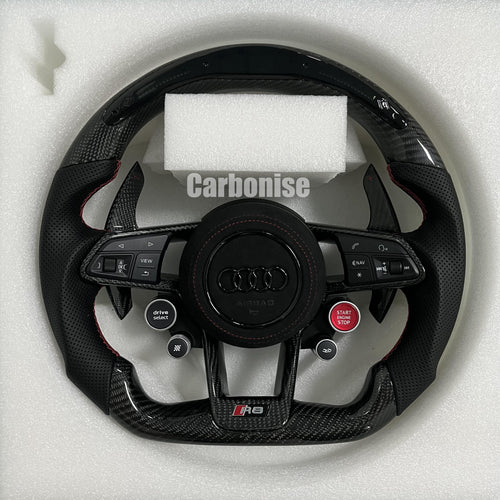 Custom Audi R8 carbon fiber steering wheel featuring integrated red Start/Stop and black Drive Select buttons, perforated leather side grips with red stitching, and a blacked-out center Audi rings emblem.