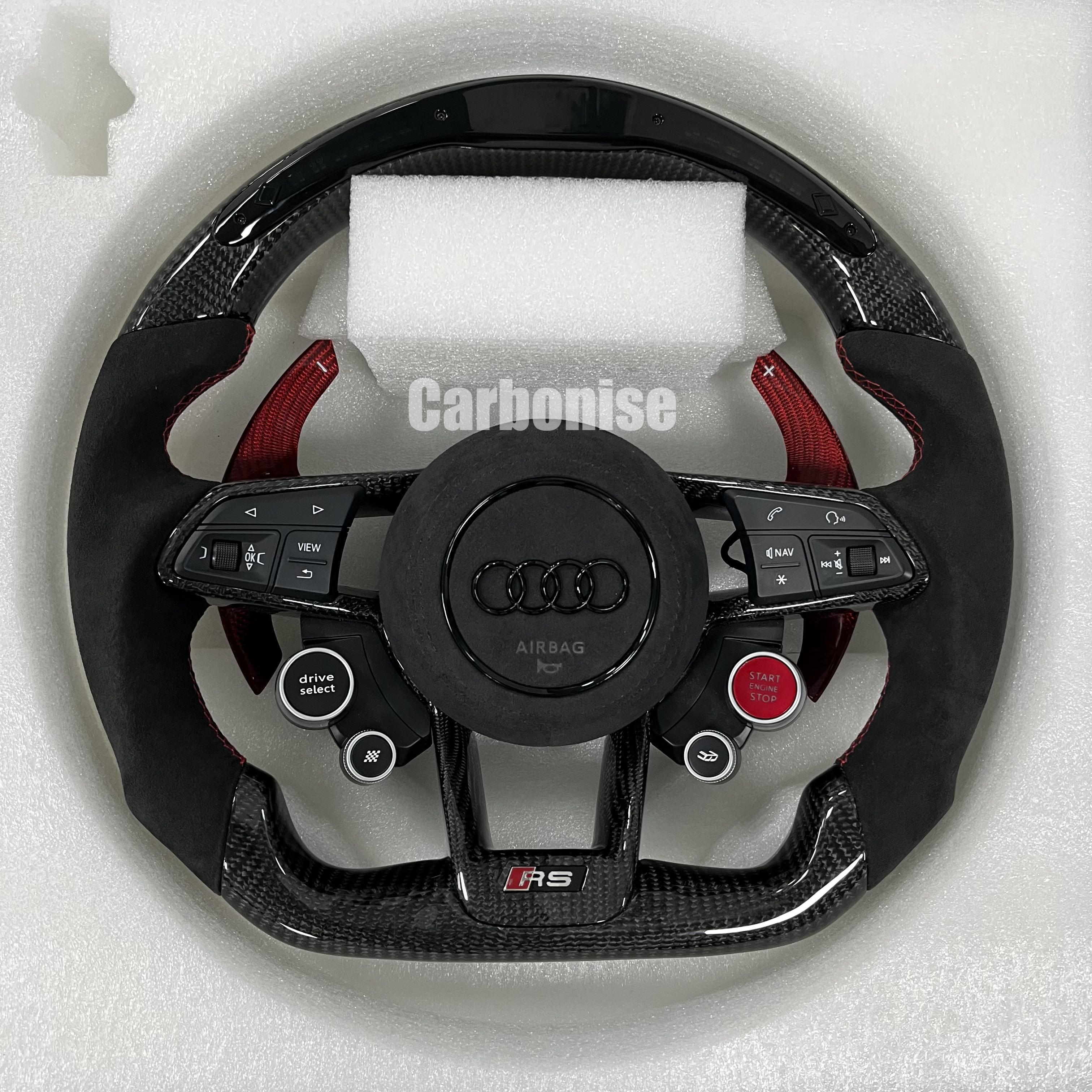 Custom Audi RS steering wheel featuring gloss carbon fiber, red-tinted carbon fiber paddle shifters, black Alcantara grips with red stitching, and integrated performance drive buttons.