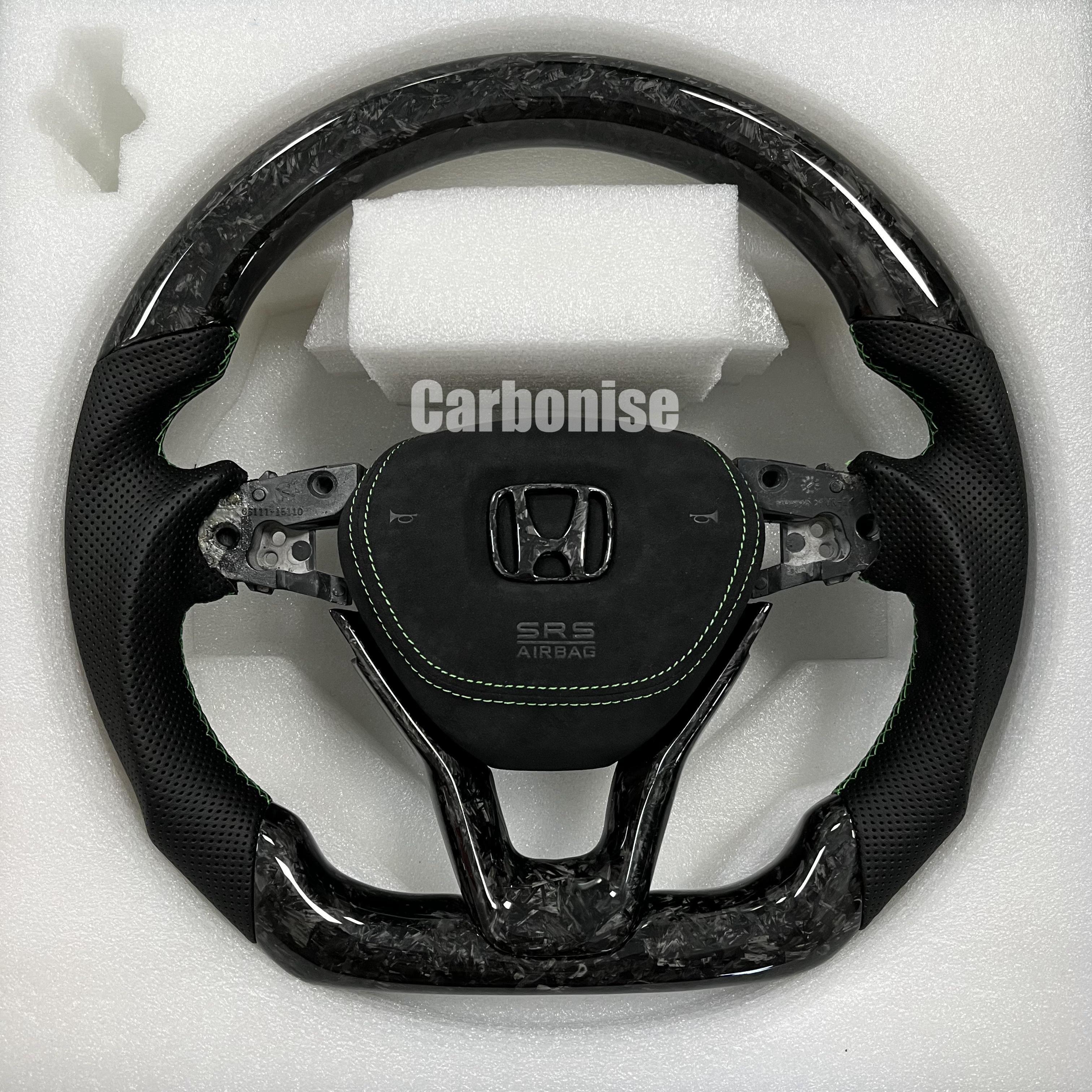 Custom Honda steering wheel with forged carbon top and bottom, black perforated leather side grips, green stitching accents, and OEM Honda airbag mount.