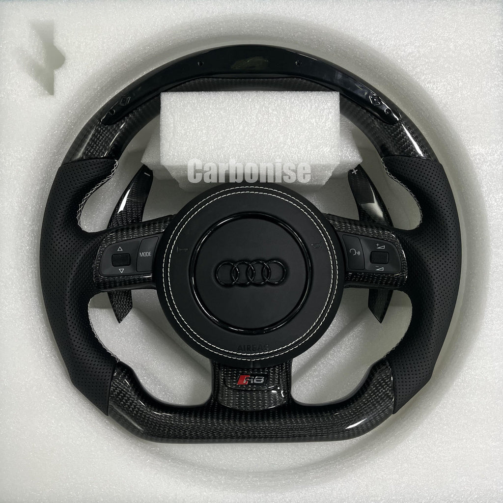 Custom Audi R8 steering wheel featuring gloss carbon fiber, integrated LED shift light display, carbon fiber paddle shifters, and perforated leather grips.