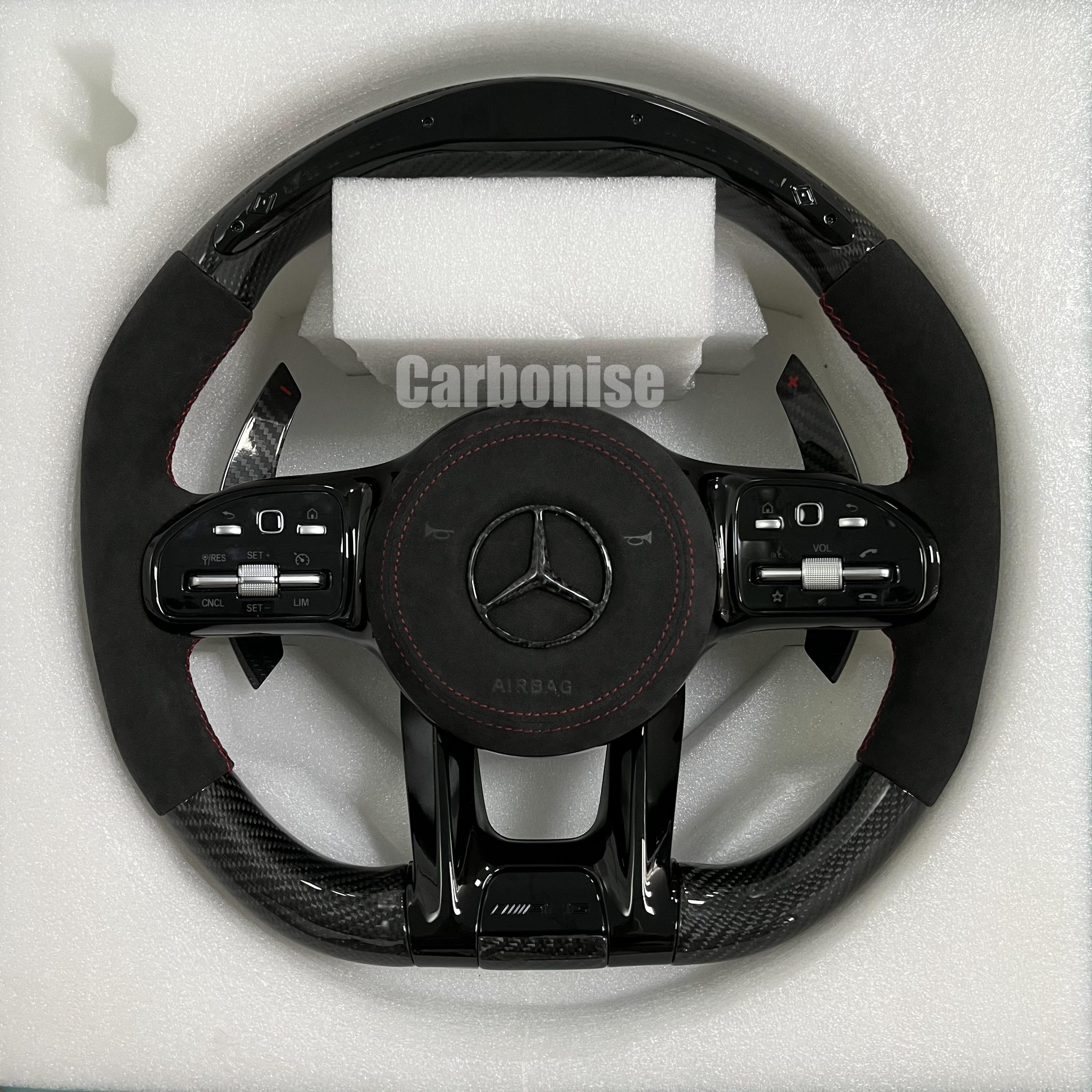 Custom Mercedes-Benz AMG steering wheel featuring high-gloss carbon fiber, black Alcantara side grips with red stitching, and integrated silver controls.