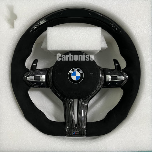 Custom BMW M Performance steering wheel featuring a full black Alcantara wrap, blue contrast stitching, and high-gloss twill carbon fiber trim on the top, bottom, and center spokes.