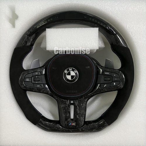 Custom BMW M performance steering wheel featuring a forged carbon fiber finish, a digital LED display, and premium black Alcantara side grips.