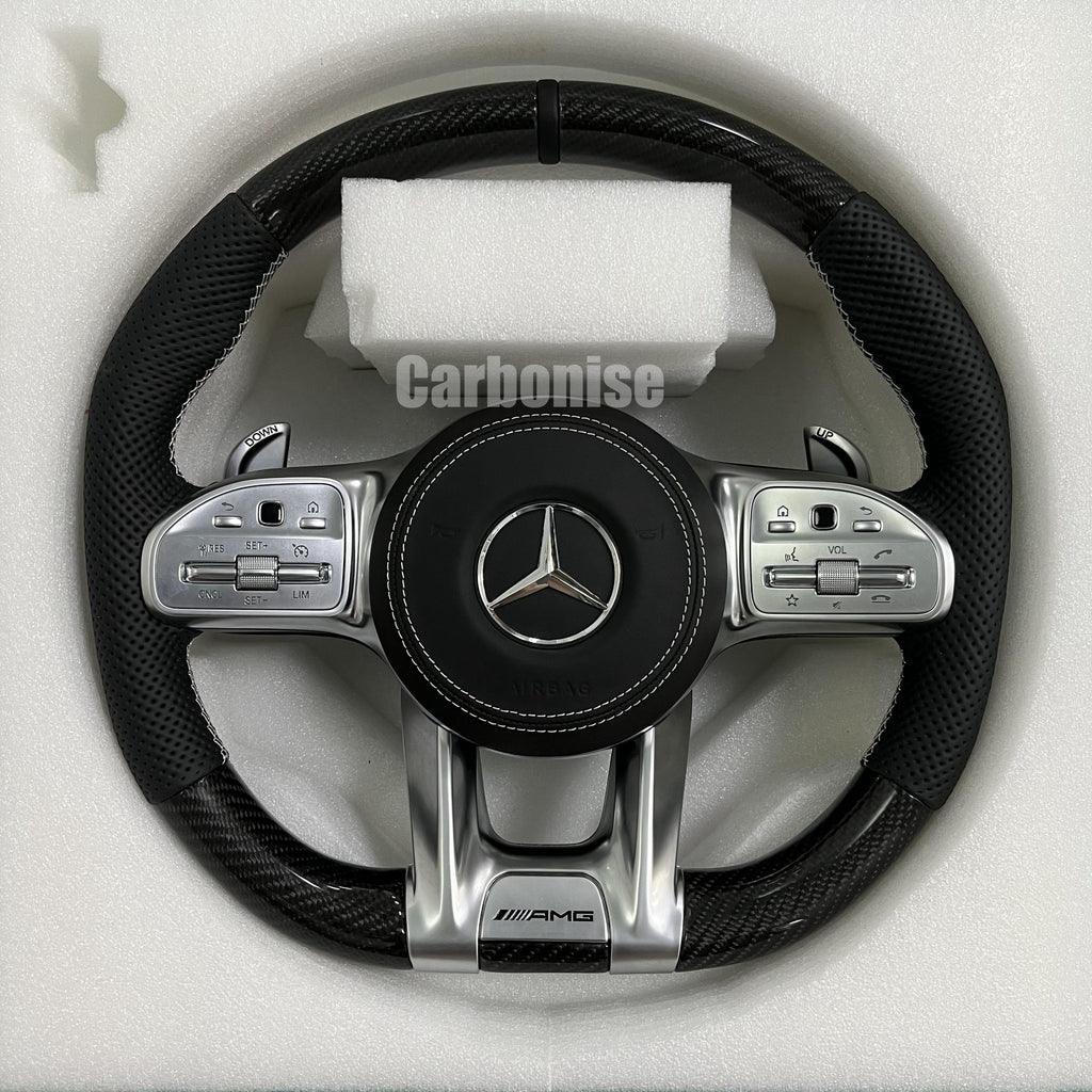 Custom Mercedes-Benz AMG performance steering wheel featuring a gloss carbon fiber top and bottom, black perforated leather grips, and silver contrast stitching.