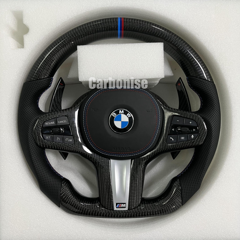Custom BMW M steering wheel featuring high-gloss carbon fiber, a signature M-tri color top racing stripe, and black perforated leather side grips.