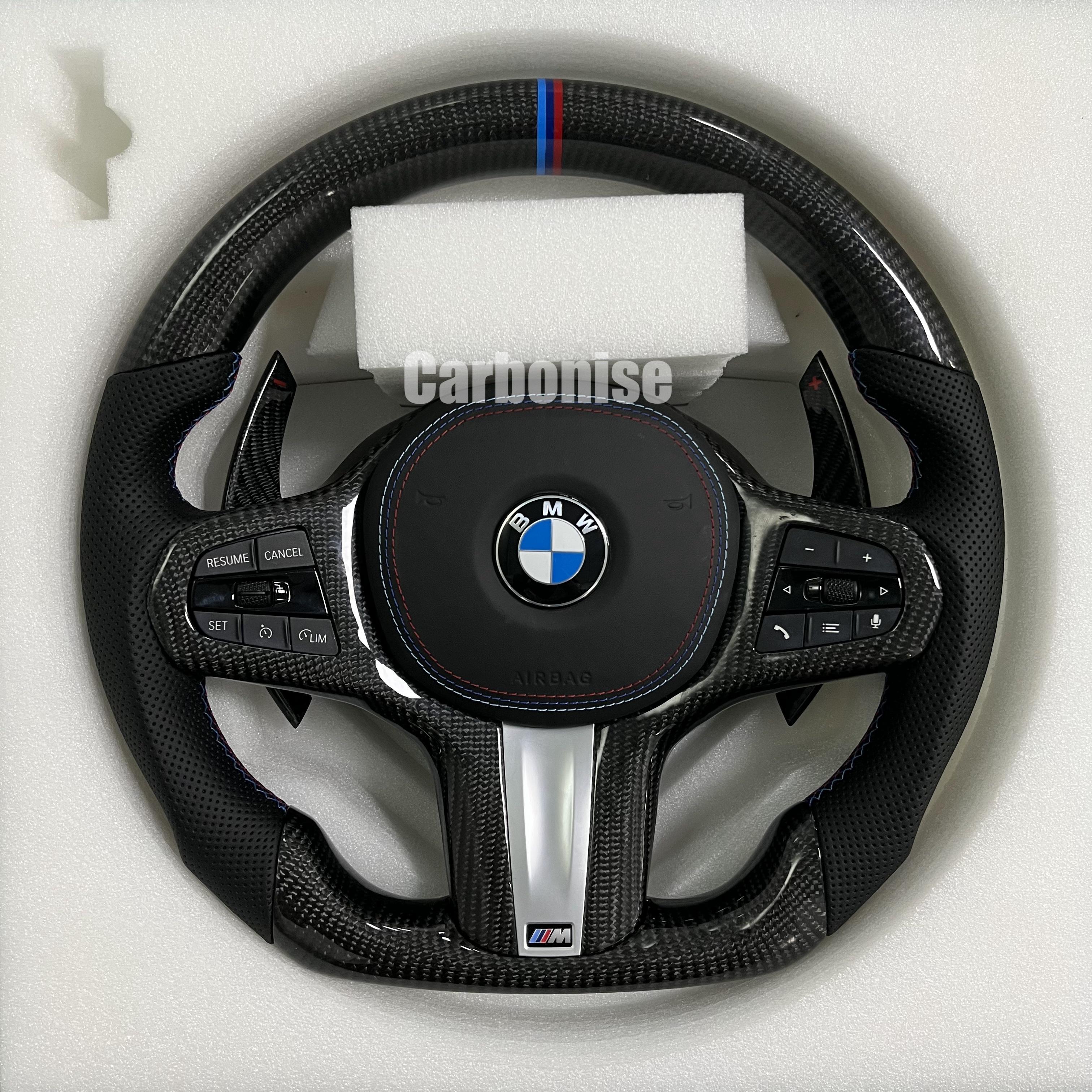 Custom BMW M steering wheel featuring high-gloss carbon fiber, a signature M-tri color top racing stripe, and black perforated leather side grips.