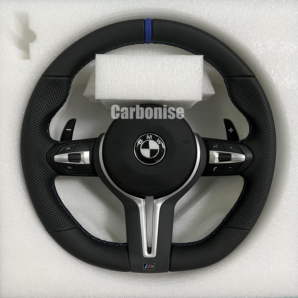 Custom BMW M steering wheel featuring a blue top racing stripe, a mix of black smooth and perforated leather grips, and blue contrast stitching.