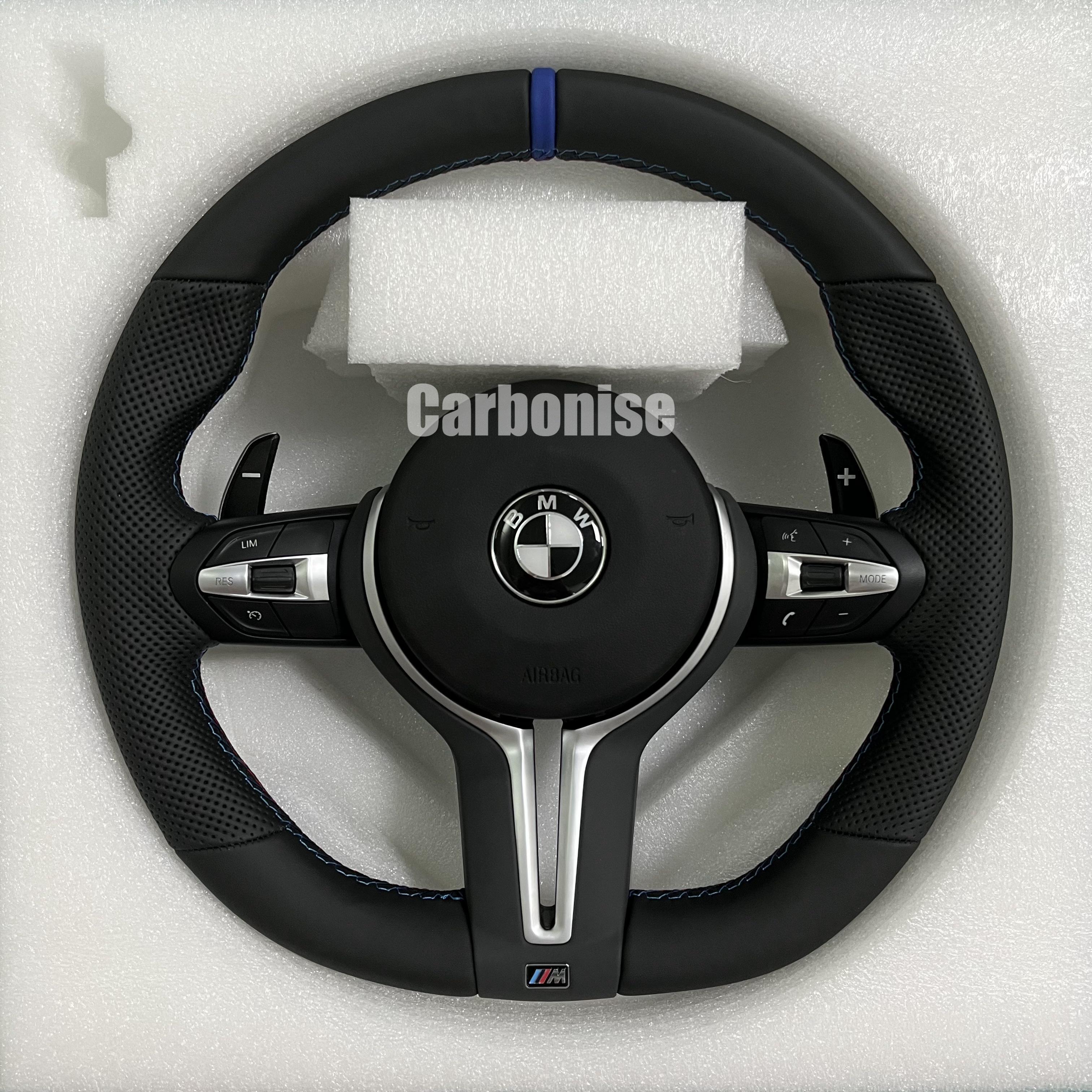 Custom BMW M steering wheel featuring a blue top racing stripe, a mix of black smooth and perforated leather grips, and blue contrast stitching.