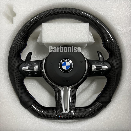 Custom BMW M performance steering wheel featuring gloss carbon fiber, black perforated leather side grips, and signature blue contrast stitching.