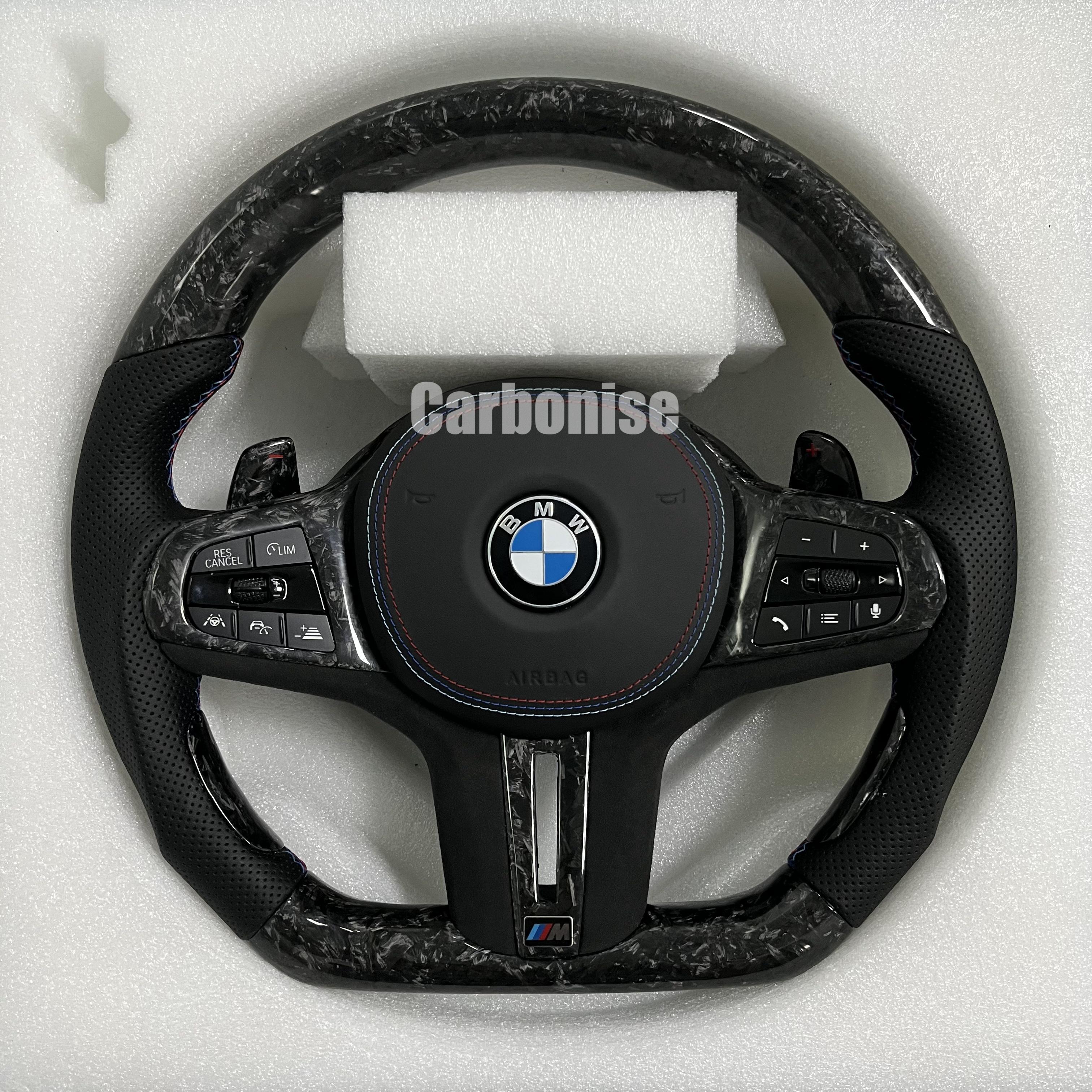 Custom BMW M performance steering wheel featuring a forged carbon fiber finish, black perforated leather side grips, and blue performance stitching.