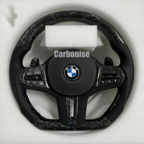 Custom BMW M performance steering wheel featuring a forged carbon fiber finish, black perforated leather side grips, and blue performance stitching.