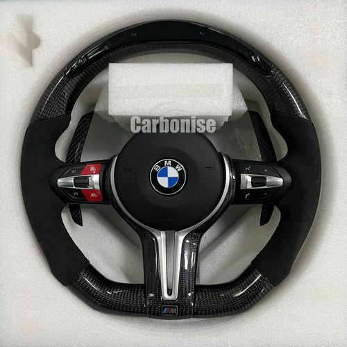 Custom BMW M performance steering wheel featuring gloss carbon fiber, black perforated leather side grips with blue stitching, and red button accents.
