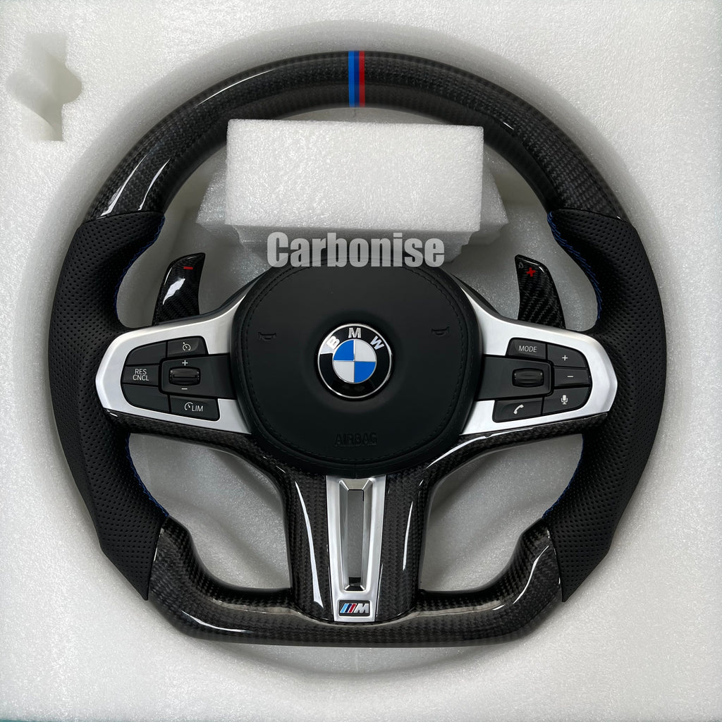 Custom BMW M steering wheel featuring high-gloss carbon fiber, a signature M-tri color top racing stripe, and black perforated leather side grips.