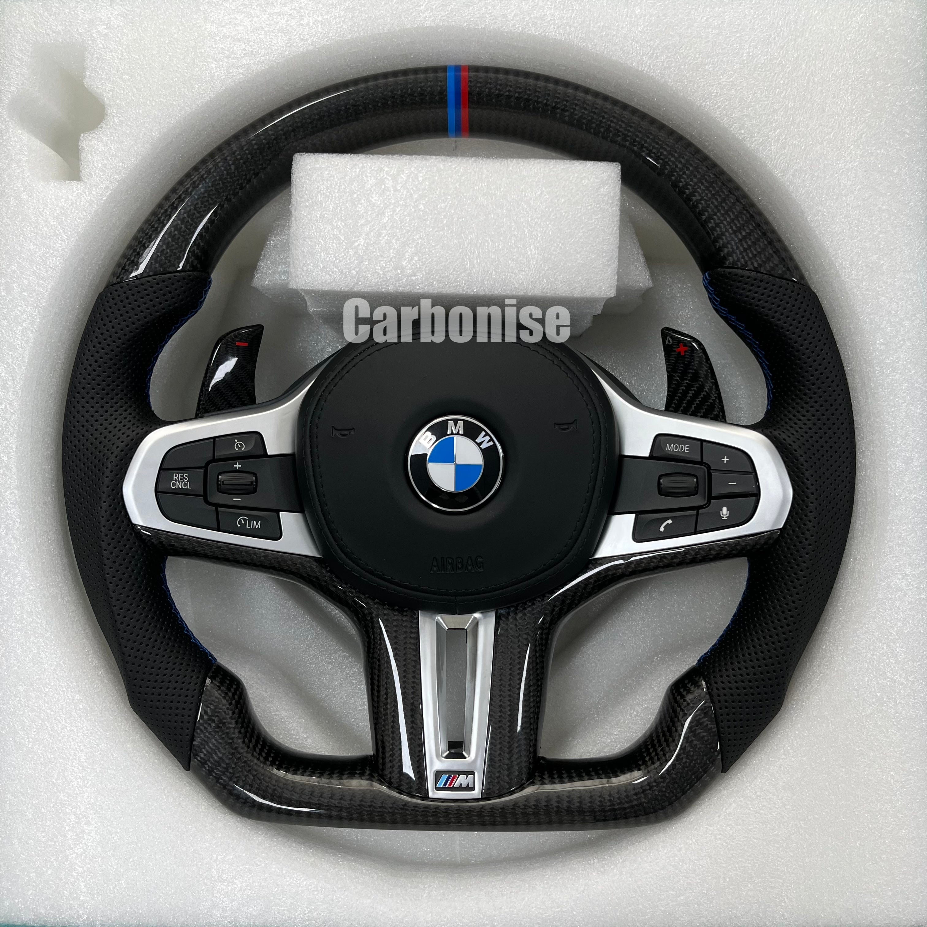 Custom BMW M steering wheel featuring high-gloss carbon fiber, a signature M-tri color top racing stripe, and black perforated leather side grips.