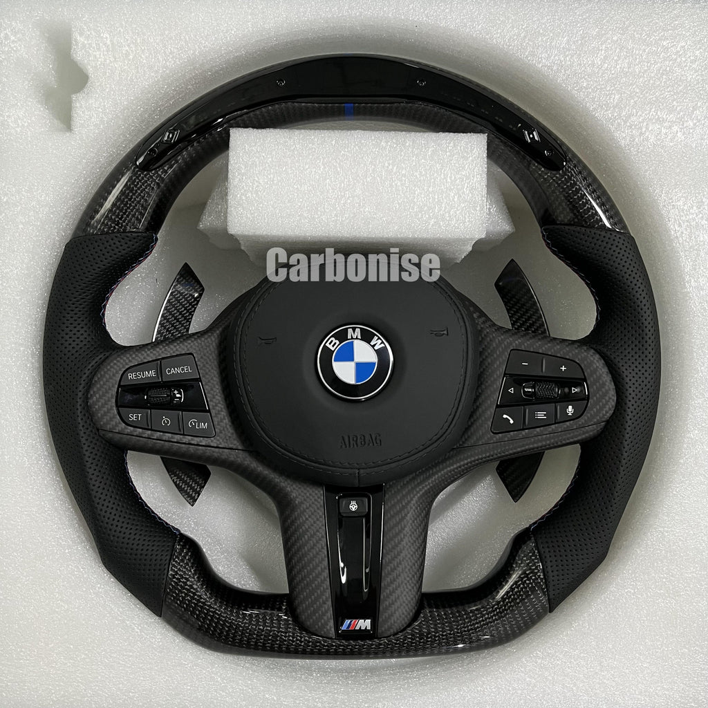 Custom BMW M performance steering wheel featuring high-gloss carbon fiber, a blue top racing stripe, and black perforated leather grips with blue stitching.