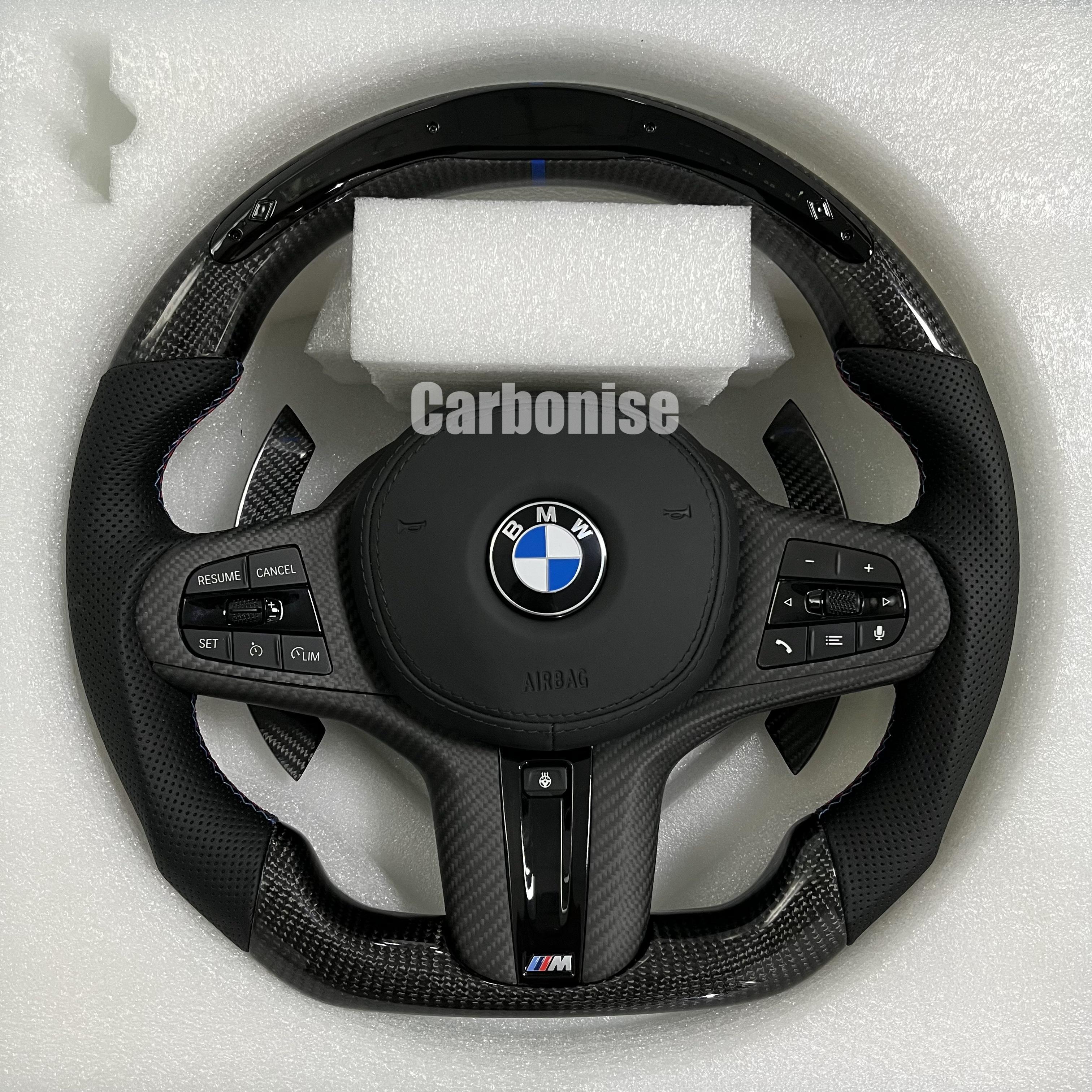 Custom BMW M performance steering wheel featuring high-gloss carbon fiber, a blue top racing stripe, and black perforated leather grips with blue stitching.