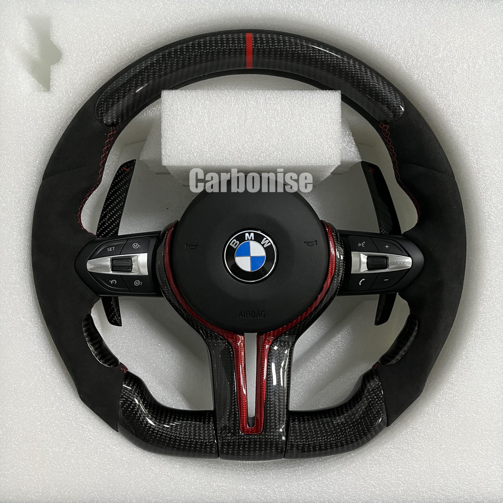 Custom BMW M performance steering wheel featuring gloss carbon fiber with red tinted accents, black Alcantara side grips, and a red racing stripe.
