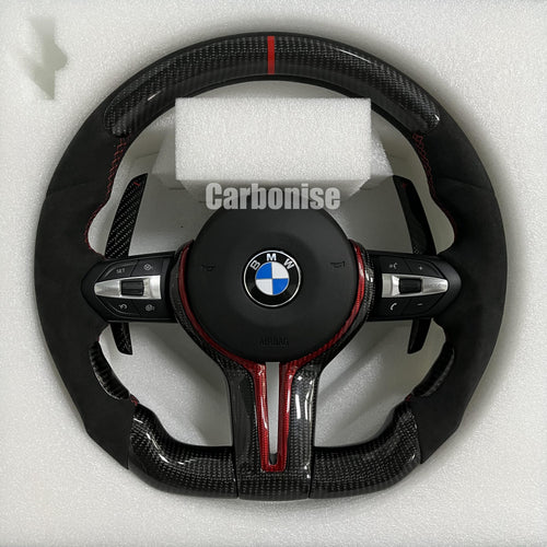 Custom BMW M performance steering wheel featuring gloss carbon fiber with red tinted accents, black Alcantara side grips, and a red racing stripe.
